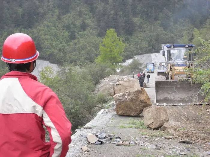 The image shows Persistent rain, as well as rock slides and a layer of mud coating on the main roads, such as the one above, hindered rescue officials' efforts to enter the target region.